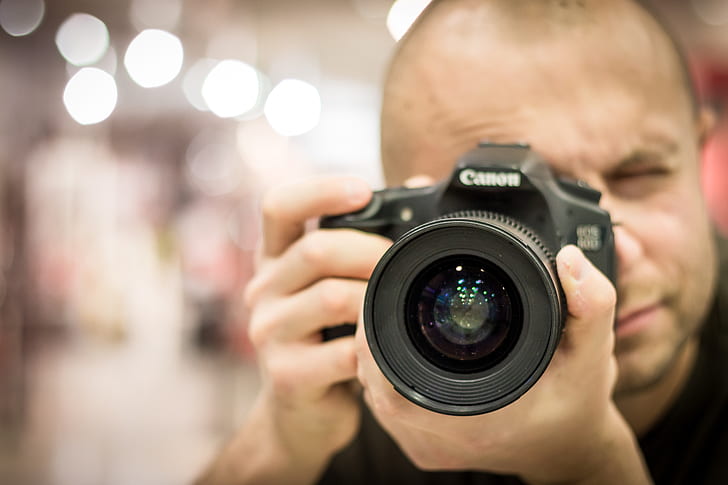 shallow focus photography of man holding DSLR camera