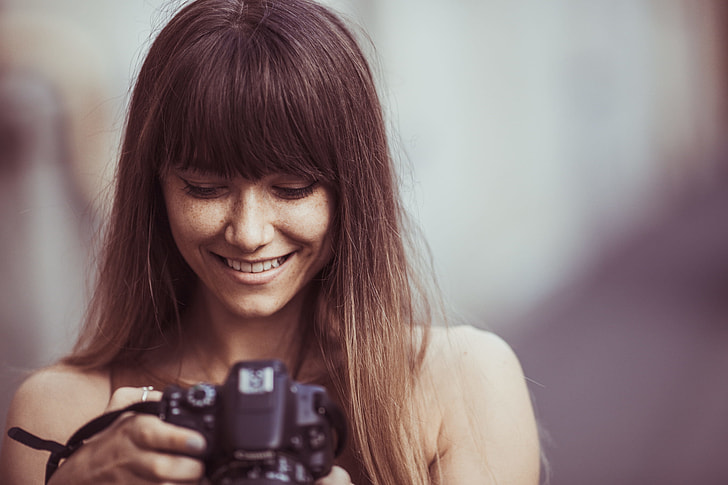 selective focus photography of woman smiling looking picture DSLR camera