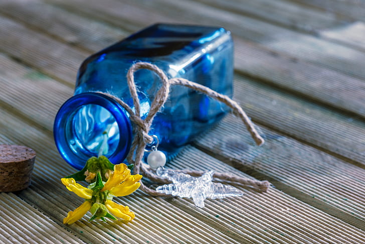 blue translucent bottle with yellow petaled flower
