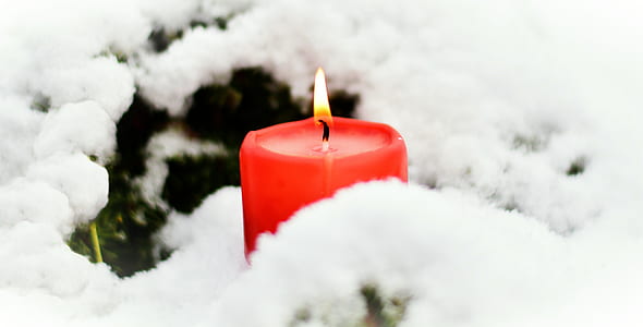 lighted red pillar candle near white snow