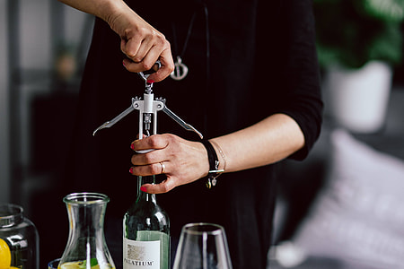 Hands opening wine bottle with corkscrew