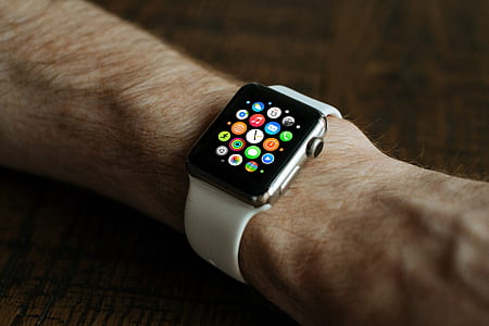 person wearing space gray Apple Watch with white sports band