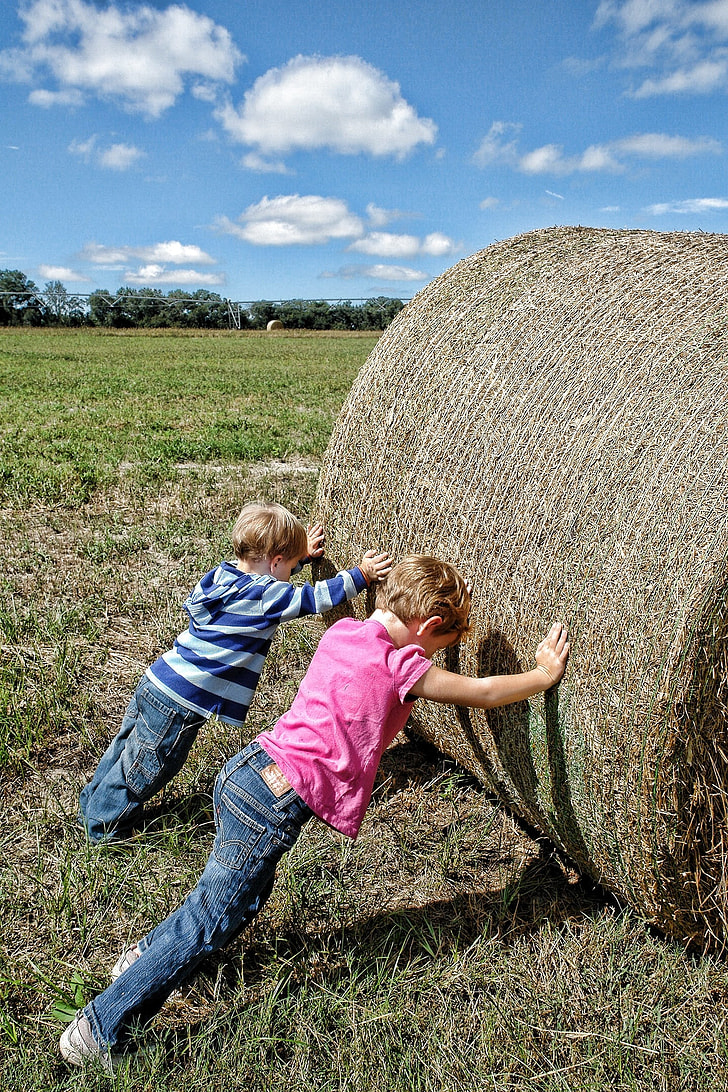 two boys pushing hay