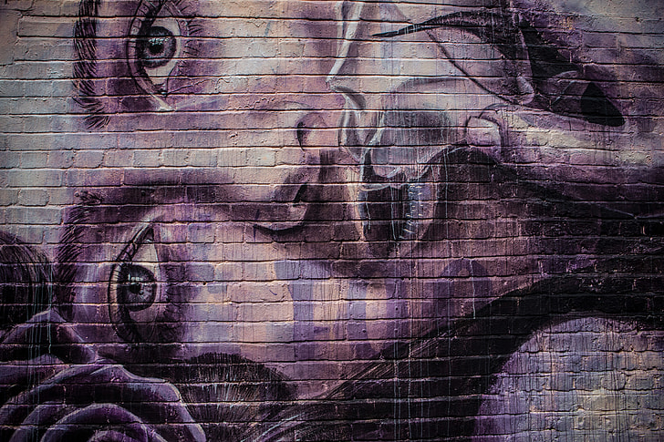 Details of purple street art applied to a brick wall in the East of London, England