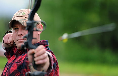 photography of man holding comound bow