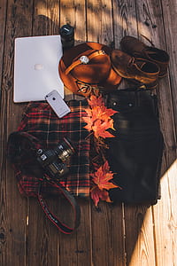 black Canon EOS 5D Mark III, space gray iPhone 6, Apple MacBook, pair of brown suede shoes, round white wristwatch with brown leather band, black denim bottoms, and red maple leaves