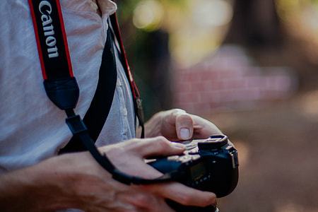 person holding black Canon DSLR camera shallow focus photography