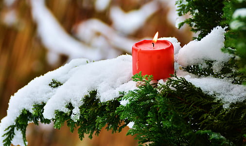 red pillar candle on white snow