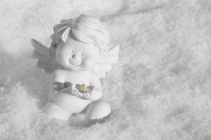 cherub white ceramic figurine sitting on the snow