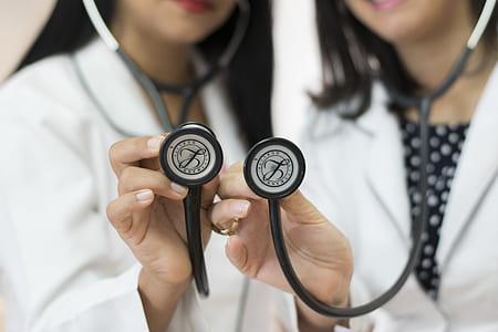 two female doctors holding two black stethoscopes