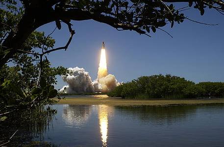 space shuttle taking off near body of water