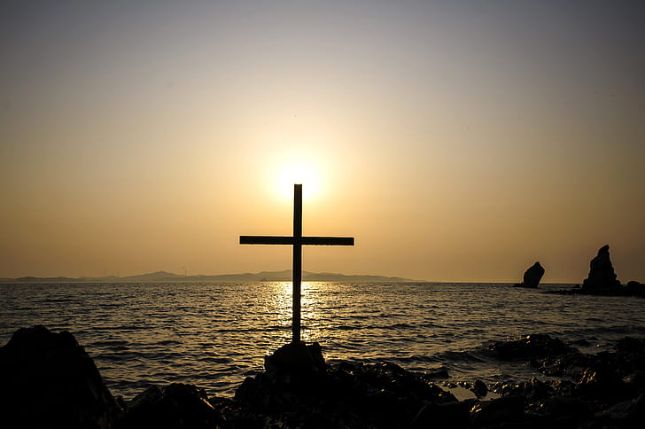 Royalty-Free photo: Silhouette of person sitting in front of cross