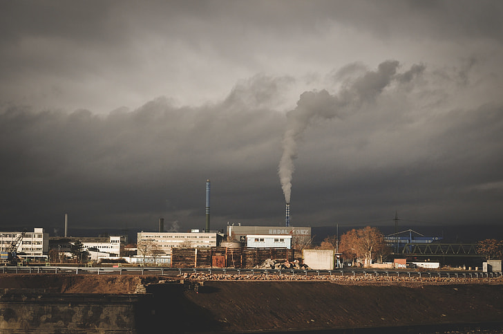 Factory releasing smoke under cloudy sky
