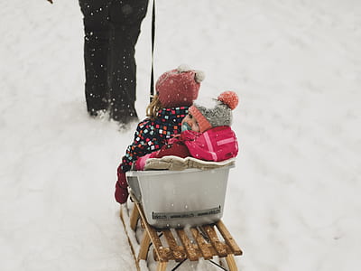 two toddler riding on snow sled