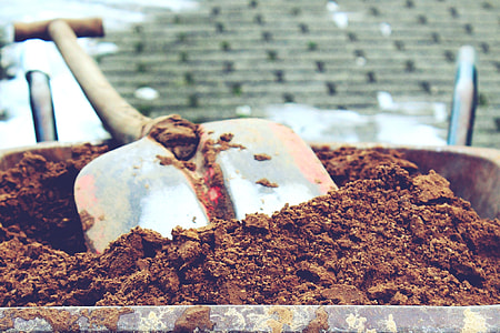 close up photo of soil in wheelbarrow with shovel