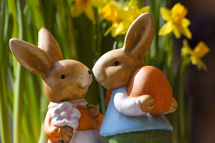 two rabbit figurines near daffodil flower