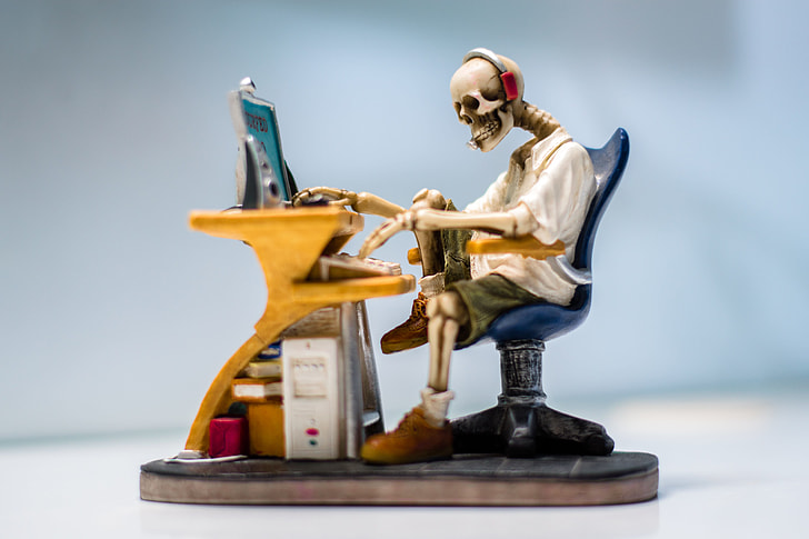 human skeleton sitting on chair in front table figure