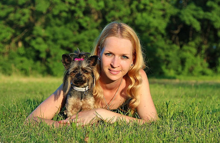 woman wearing black tank top lying on green grass field with black and tan Yorkshire terrier puppy during daytime