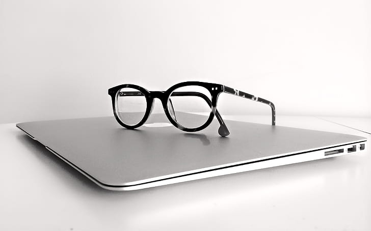 black framed clubmaster-style eyeglasses on top of MacBook Air
