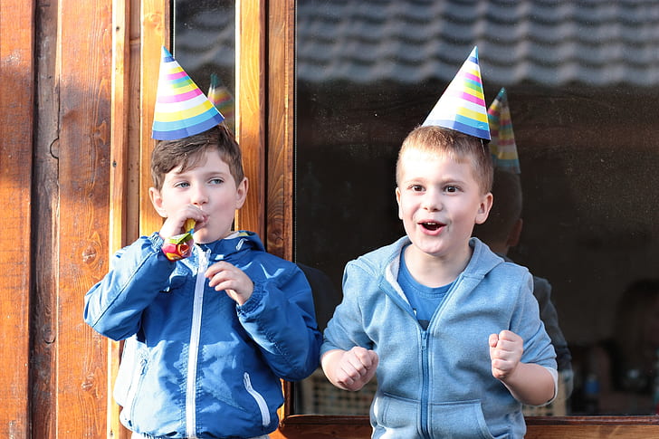 two boys wearing jackets and party cones