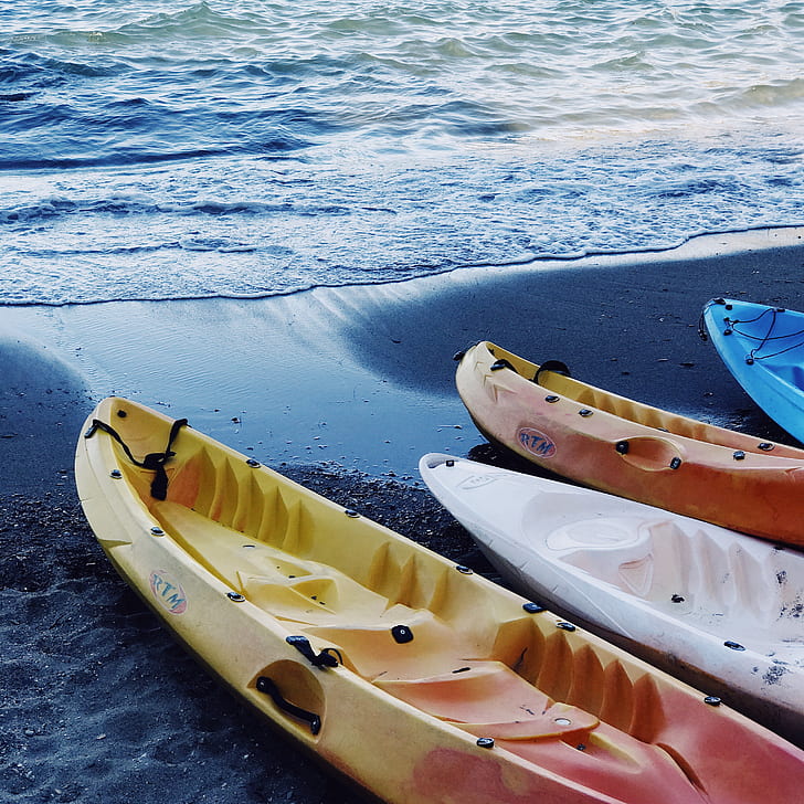closeup photography of four kayaks in line on seashore