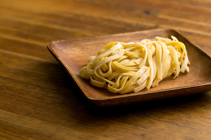 cooked flat pasta on brown wooden plate