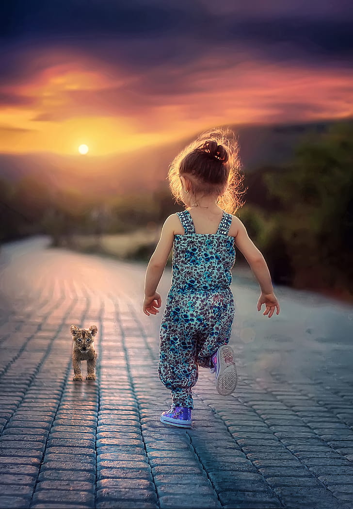 girl wearing blue and black leopard pattern overalls running toward leopard cub