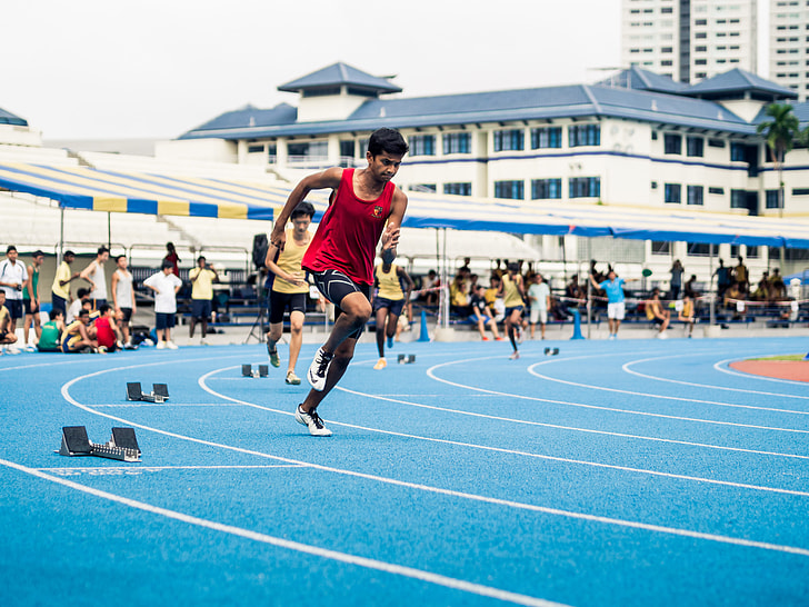 men racing on track and field at daytime