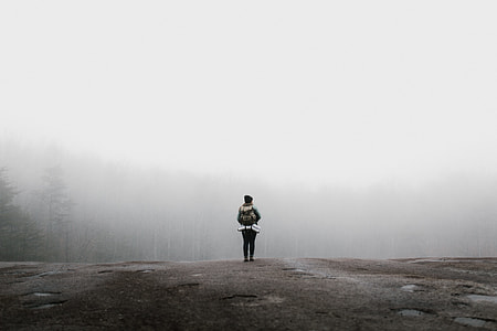 person standing on ledge covered by fog