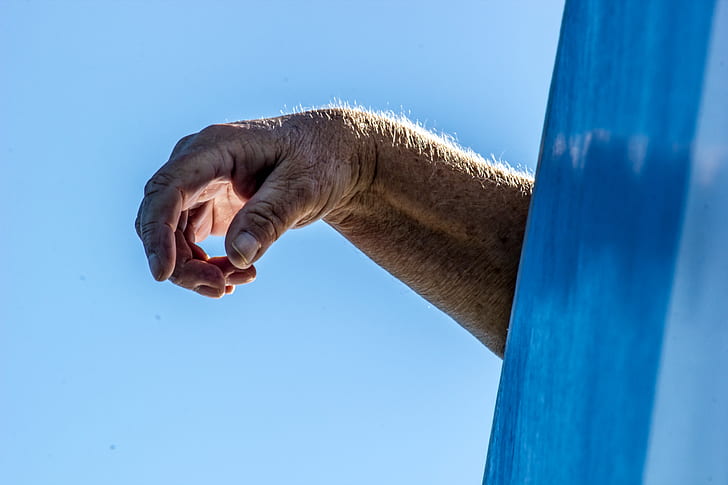 photo of human hand under blue sky