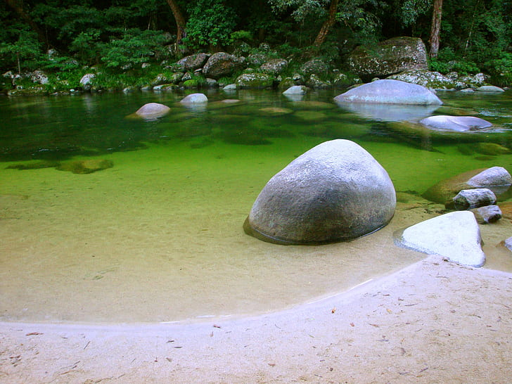 calm body of water with rocks surrounded trees