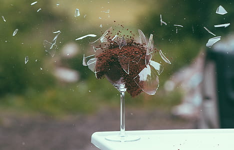 selective photography of broken wineglass filled with brown powder