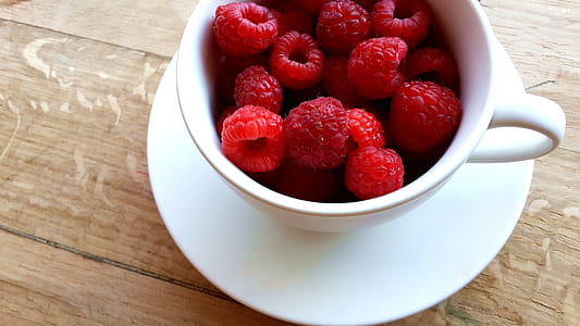 bunch of raspberries in white ceramic teacup