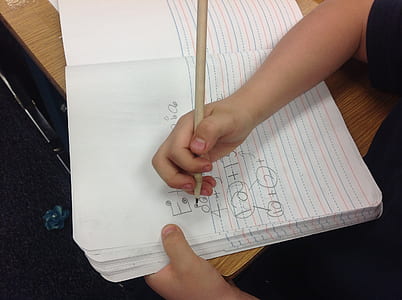 child holding writing paper and pencil