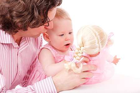 baby wearing pink dress holding doll