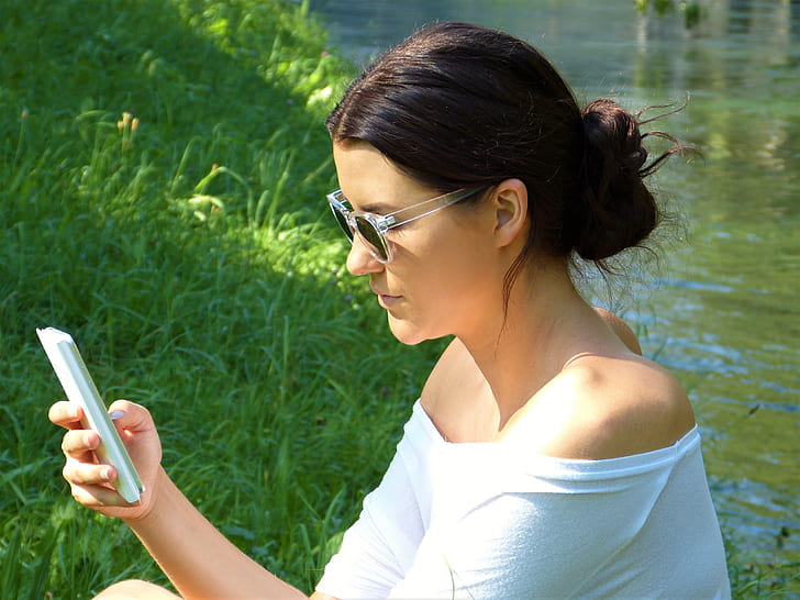 woman using smartphone near river
