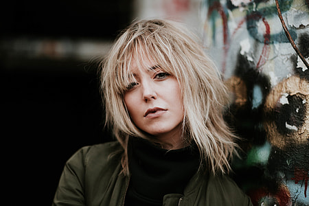 portrait of blonde woman in brown zip-up jacket and black turtle neck