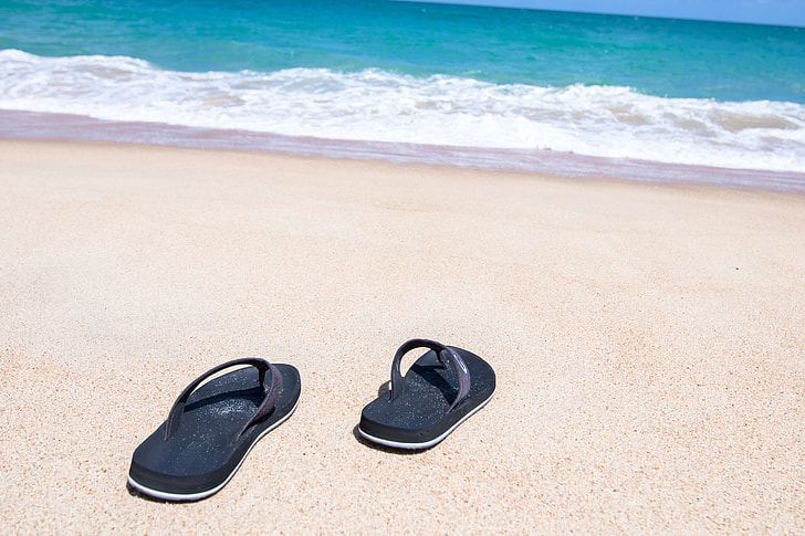 pair of black flip-flops in seashore