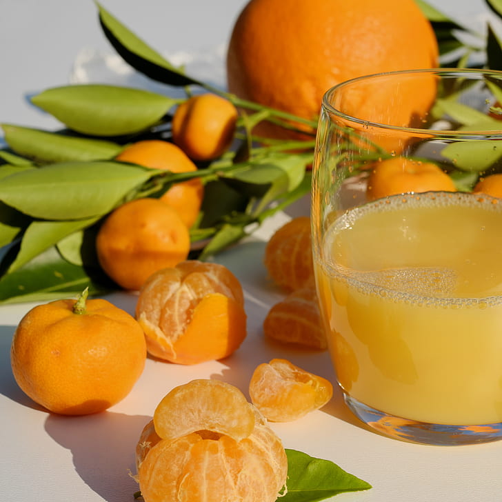 bunch of oranges near filled clear drinking glass