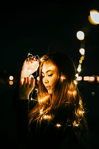woman holding string lights during night time
