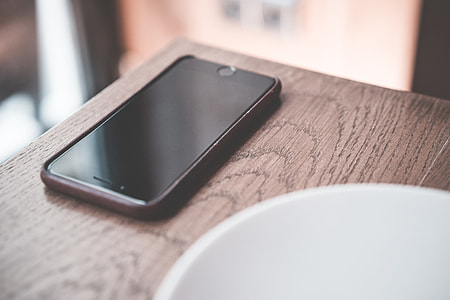 Black Smartphone on Wooden Table in Café