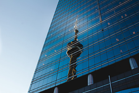 brown statue reflect on blue glass high rise building