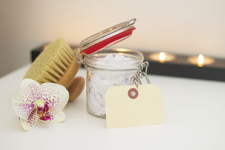 clear glass container, white and purple orchid flower, and brush