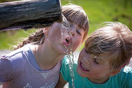 two girls drinking water during daytime