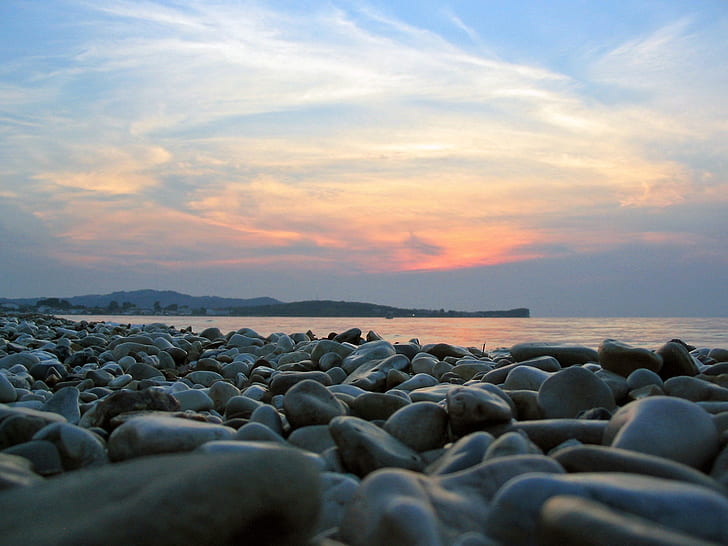black pebbles near ocean during golden hours
