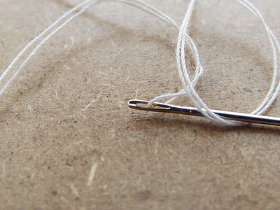 stainless steel needle with white thread photograph