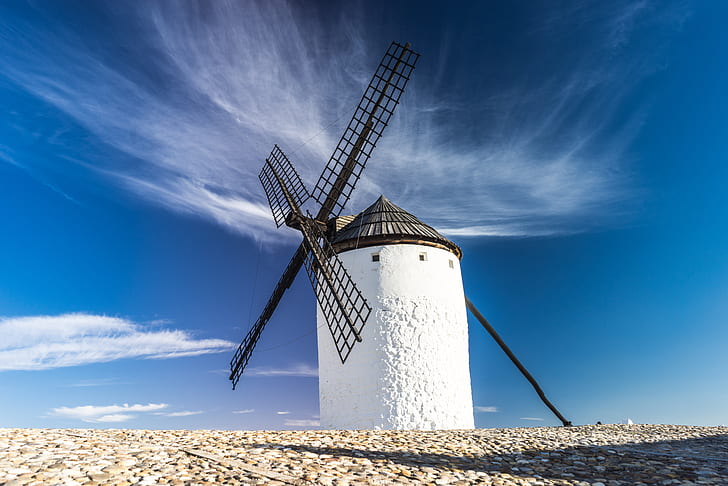 white lighthouse with black windmill under white clouds photography