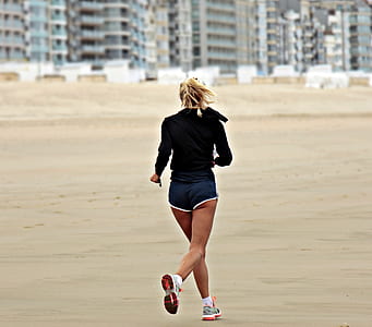 woman wearing black long-sleeved top and blue boy shorts on a early jog