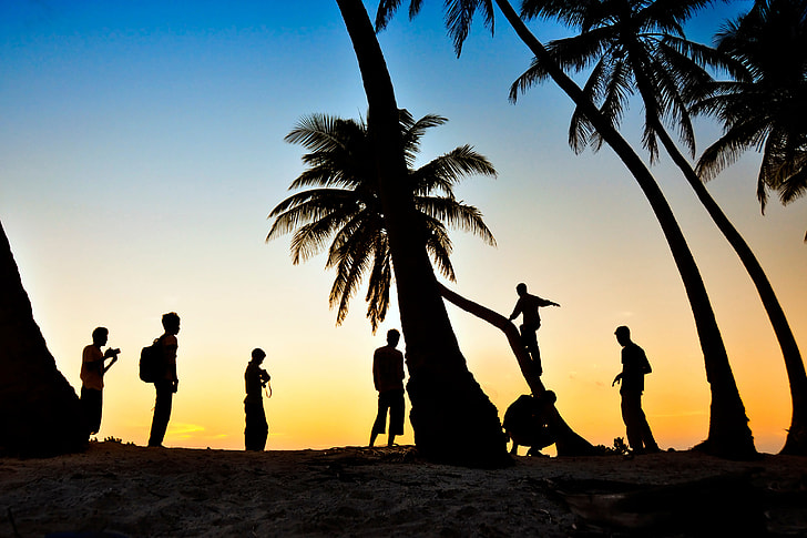 People enjoying the palm-tree beach at sunset in the Maldives