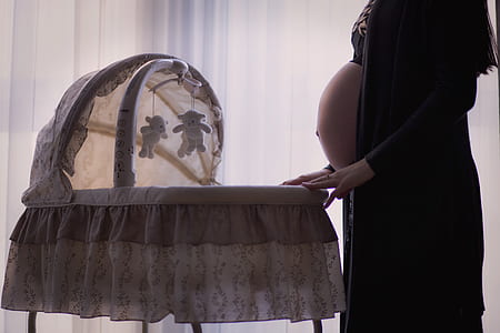 woman in black cardigan in front of white bassinet